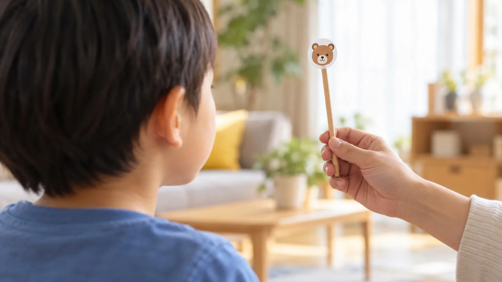 大人が持つ棒の先のクマのシールを、目で追いかけている子ども